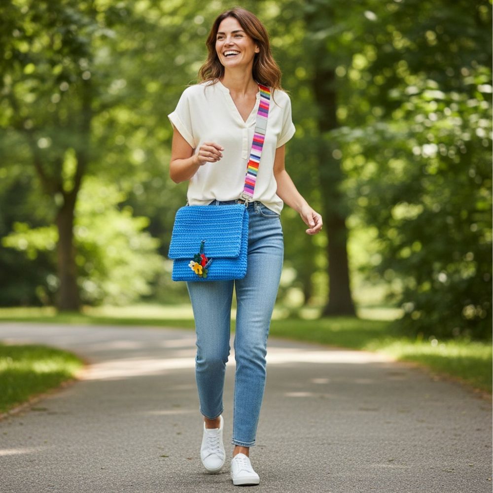 Frau trägt große blaue Häkeltasche Blue Bloom #154 mit buntem Schultergurt als Crossbody Tasche im Alltag