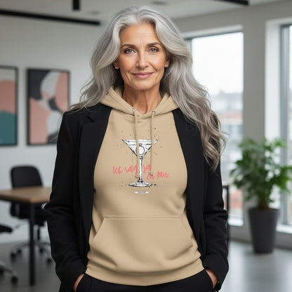 Frau mit grauen Haaren trägt sandfarbenen Hoodie mit Cocktailglas-Motiv und Schriftzug Ich sag ja. Zu mir. in Koralle, dazu schwarzer Blazer, modernes Büro im Hintergrund