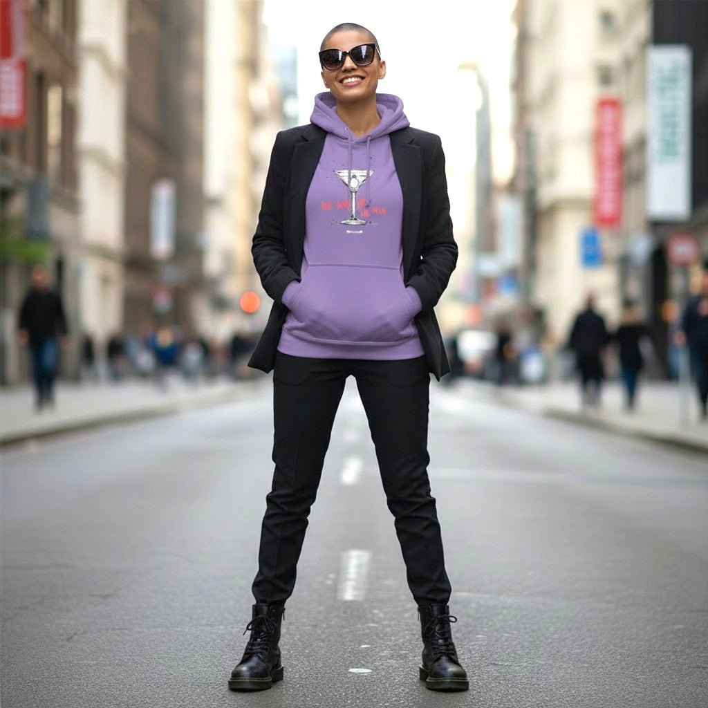 Frau mit kurzrasiertem Haar und Sonnenbrille trägt lavendelfarbenen Hoodie mit Cocktailglas-Motiv und Schriftzug Ich sag ja. Zu mir. in Koralle, dazu schwarzer Blazer und Boots, urbane Straßenszene