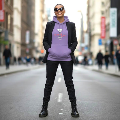 Frau mit kurzrasiertem Haar und Sonnenbrille trägt lavendelfarbenen Hoodie mit Cocktailglas-Motiv und Schriftzug Ich sag ja. Zu mir. in Koralle, dazu schwarzer Blazer und Boots, urbane Straßenszene