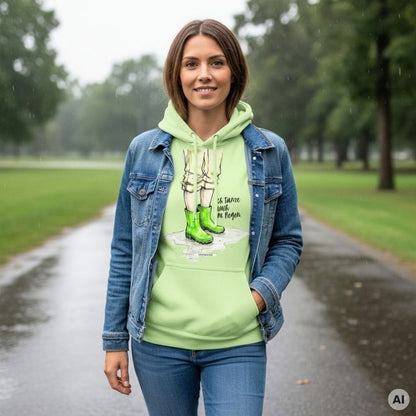Frau mit Bob und Jeansjacke trägt den HOOKamSEE Statement-Hoodie Ich tanze auch im Regen. in Pistazie auf einem nassen Parkweg