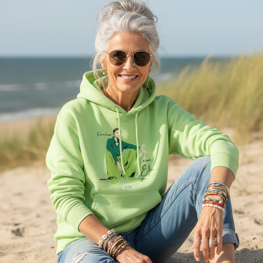 Frau trägt pistaziefarbenen HOOKamSEE Hoodie Karma kennt keine Eile in den Dünen