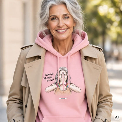 Frau mit grauen Haaren im Trenchcoat trägt einen rosa Hoodie mit Yoga-Aquarell-Motiv, gefalteten Händen und Schriftzug auf der Brust