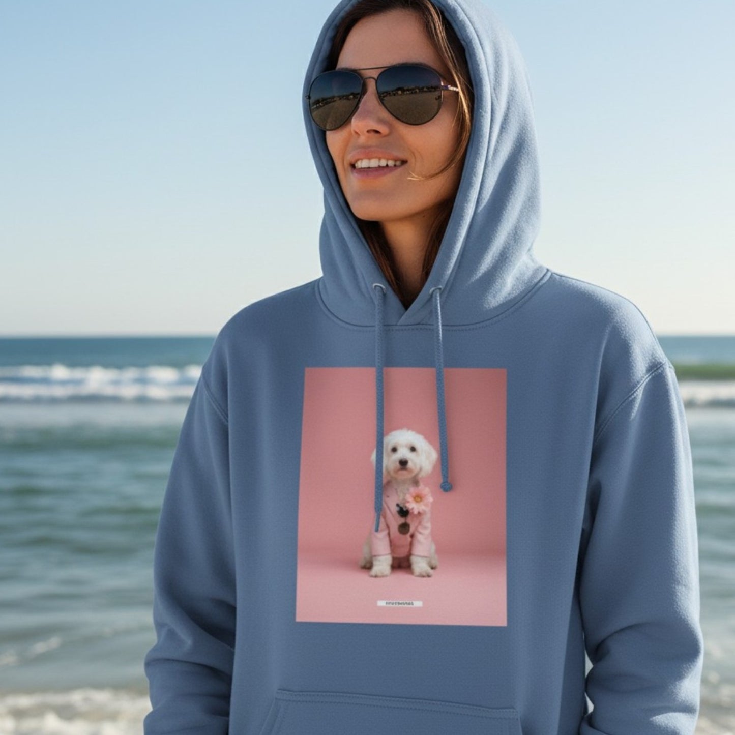 Lachende Frau mit Sonnenbrille trägt den HOOKamSEE Hoodie Styled Dogs Maltipoo in Carolina Blue am Strand