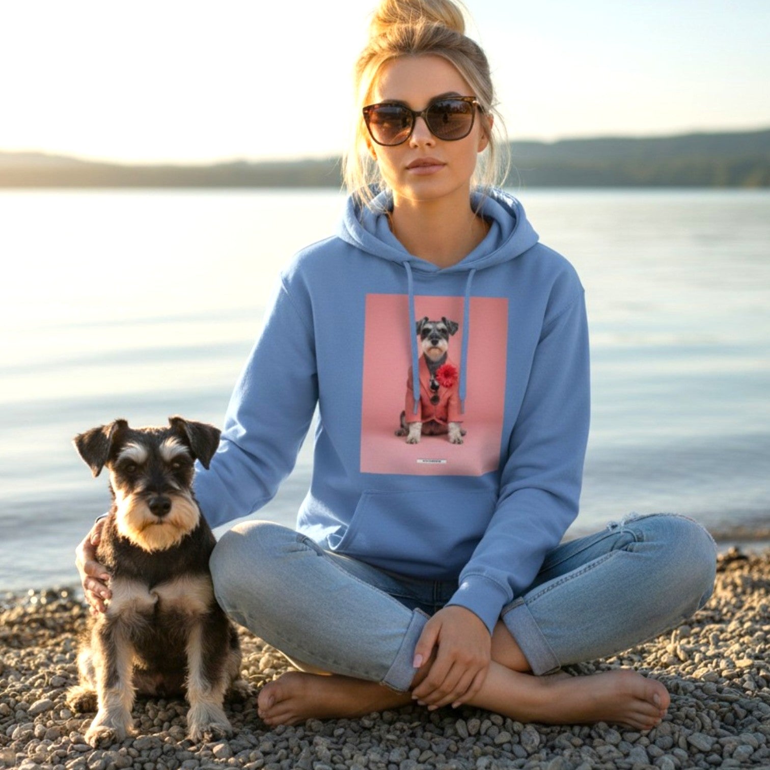 Blonde Frau sitzt mit echtem Schnauzer am See bei Sonnenuntergang und trägt den HOOKamSEE Hoodie Styled Dogs Schnauzer in Carolina Blue