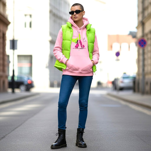 Frau mit kurzrasiertem Haar trägt HOOKamSEE Hoodie Karma kommt auf High Heels in Hellrosa mit Neongrüner Steppweste, Jeans und Boots in urbaner Straßenkulisse