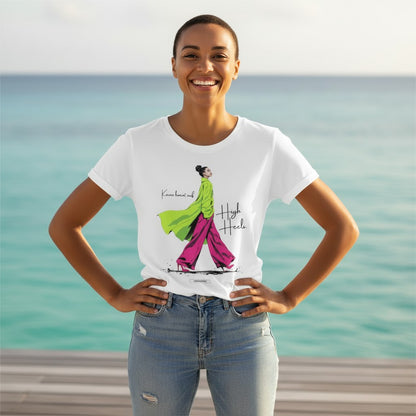Frau trägt weißes Premium T-Shirt Karma kommt auf High Heels von HOOKamSEE vor türkisblauem Meer
