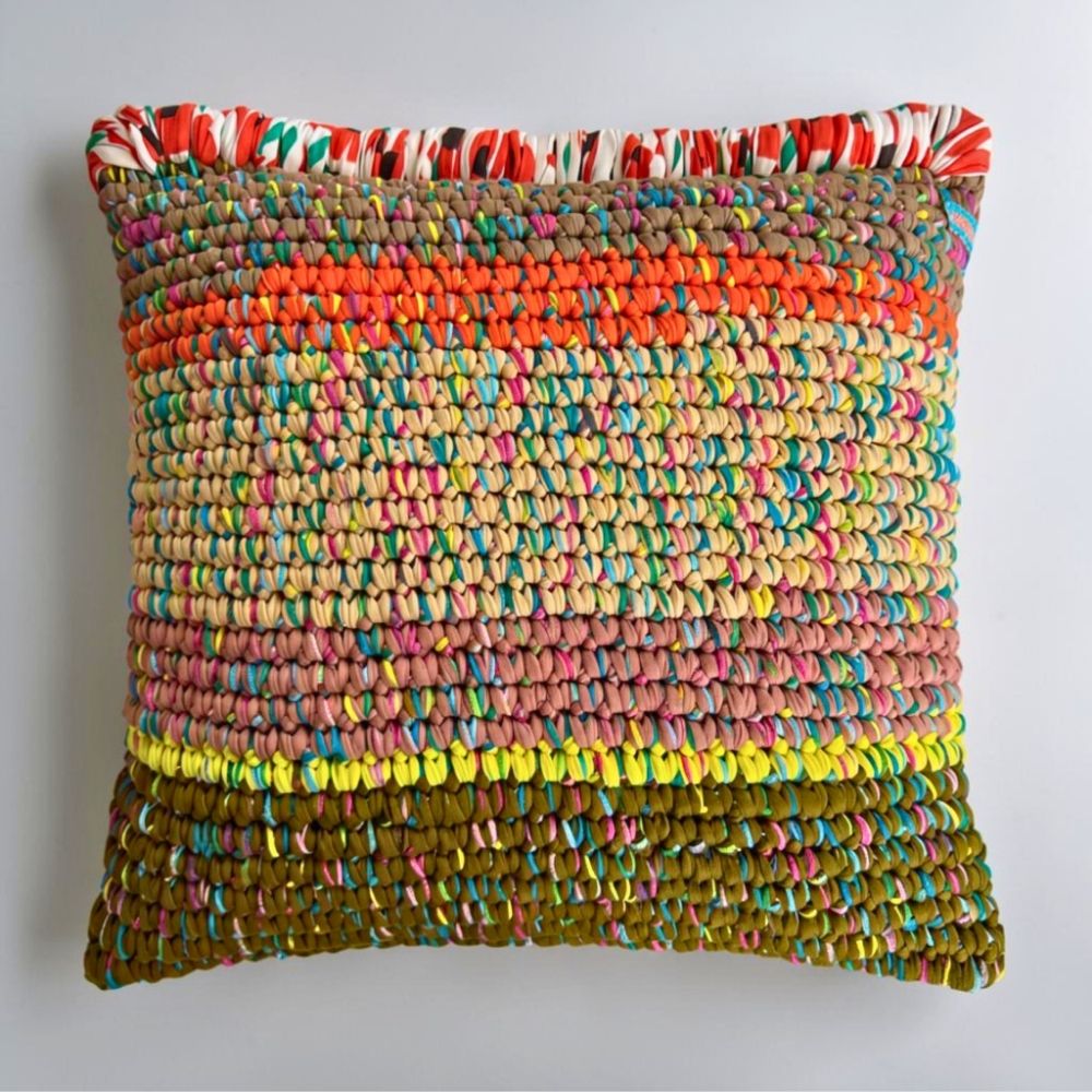 Coiled-Crochet-Kissen Amber Harvest 45×45 cm in Khaki, Orange, Sandbeige und Olivgrün mit gemusterter Wickelkante in Rot-Weiß-Grün, Frontalansicht.