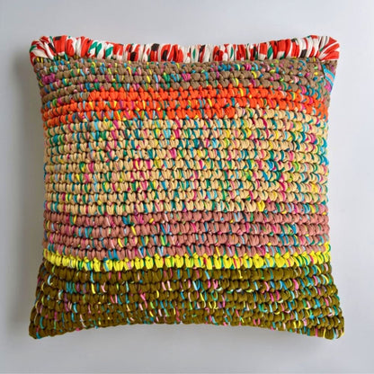 Coiled-Crochet-Kissen Amber Harvest 45×45 cm in Khaki, Orange, Sandbeige und Olivgrün mit gemusterter Wickelkante in Rot-Weiß-Grün, Frontalansicht.