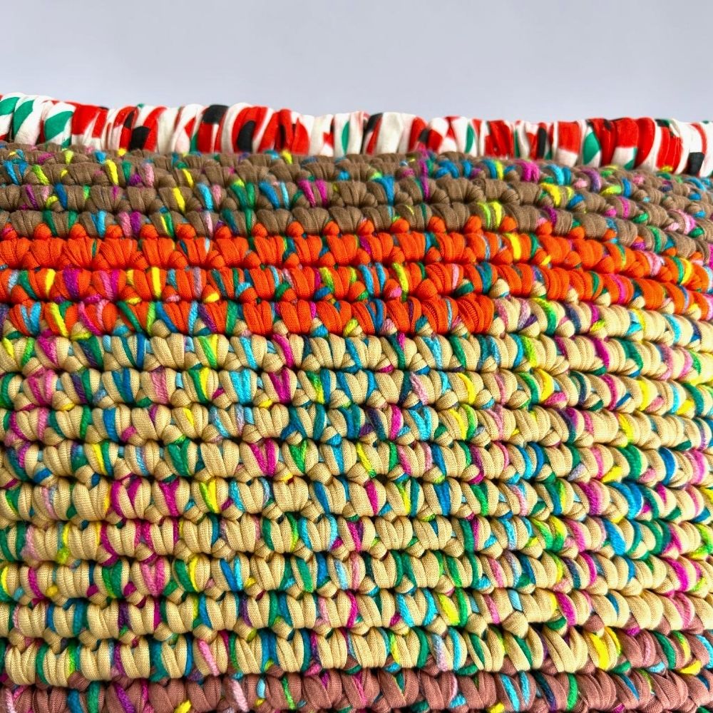 Detailansicht der Reihenstruktur des Coiled-Crochet-Kissens Amber Harvest mit Farbverlauf von Khaki über Orange zu Sandbeige.