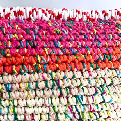 Makroaufnahme der reliefartigen Häkelstruktur in Pink, Orange, Creme, Türkis und Braun