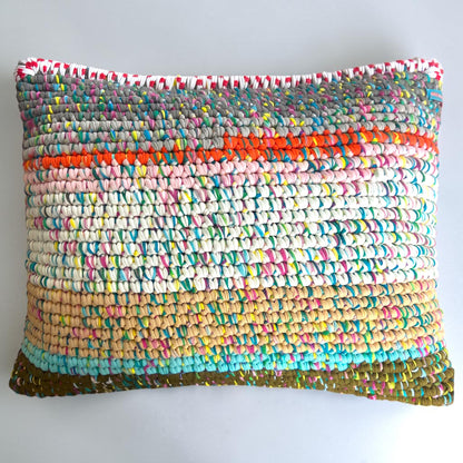 Kissen Meadow Confetti 55×45, Coiled-Crochet-Unikat #182, Gesamtansicht mit Farbverlauf von Grau über Orange, Rosa, Creme bis Türkis und Olivgrün