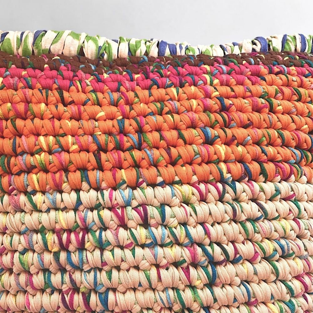Nahaufnahme der Coiled-Crochet-Struktur, Terrakotta-Orange und Sandrosé mit bunten Garneinschlüssen