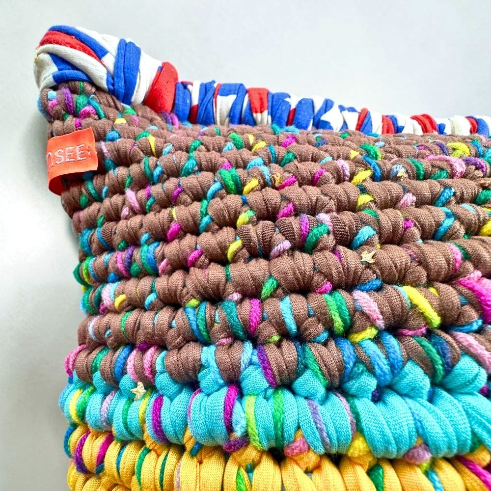 Detailaufnahme der Coiled-Crochet-Struktur von Kissen Saffron Clay in Taupe-Braun, Türkis und Ocker-Gelb mit sichtbarem HOOKamSEE-Label
