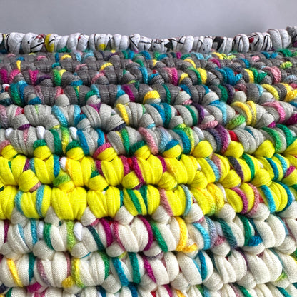 Nahaufnahme der Coiled-Crochet-Struktur des Kissens Sundown Grey, Detail der oberen Kante mit Strichzeichnungen auf hellgrauem Grund und HOOKamSEE-Label
