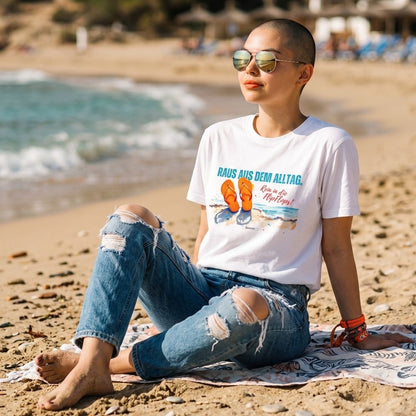 Model am Strand mit weißem HOOKamSEE Shirt und sommerlichem FlipFlops-Motiv am Meer.