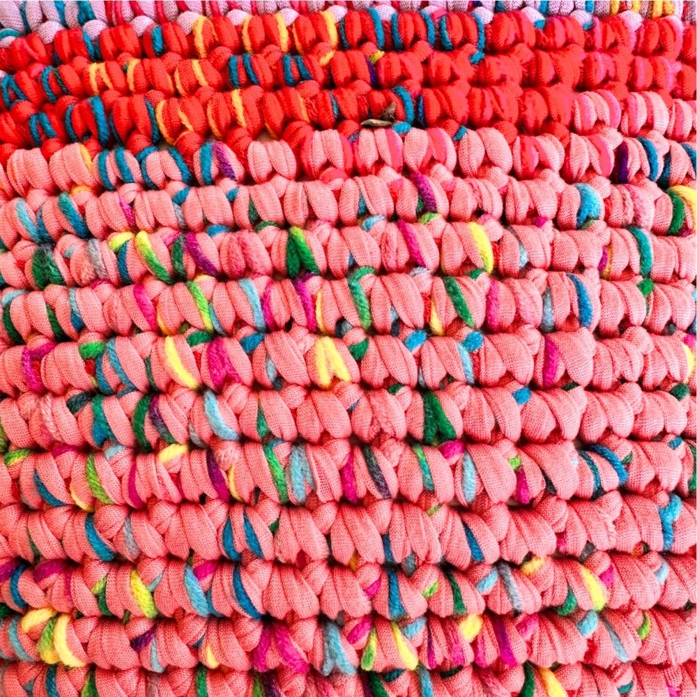 Extreme Nahaufnahme der Coiled-Crochet-Oberfläche in Rot und Koralle mit bunten Farbakzenten