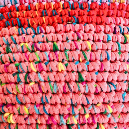 Extreme Nahaufnahme der Coiled-Crochet-Oberfläche in Rot und Koralle mit bunten Farbakzenten