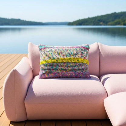 Kissen Lagoon Mosaic auf einem rosafarbenen Sofa an einem Seesteg, ruhige Wasserfläche im Hintergrund